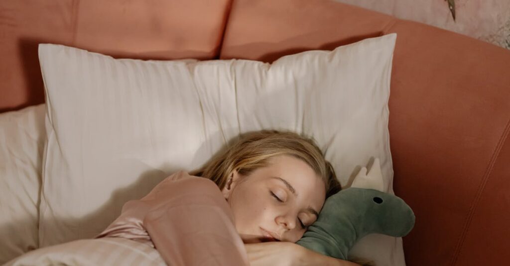 A woman in pajamas peacefully sleeping in bed, cuddling a plush toy, with a floral-themed wall behind.